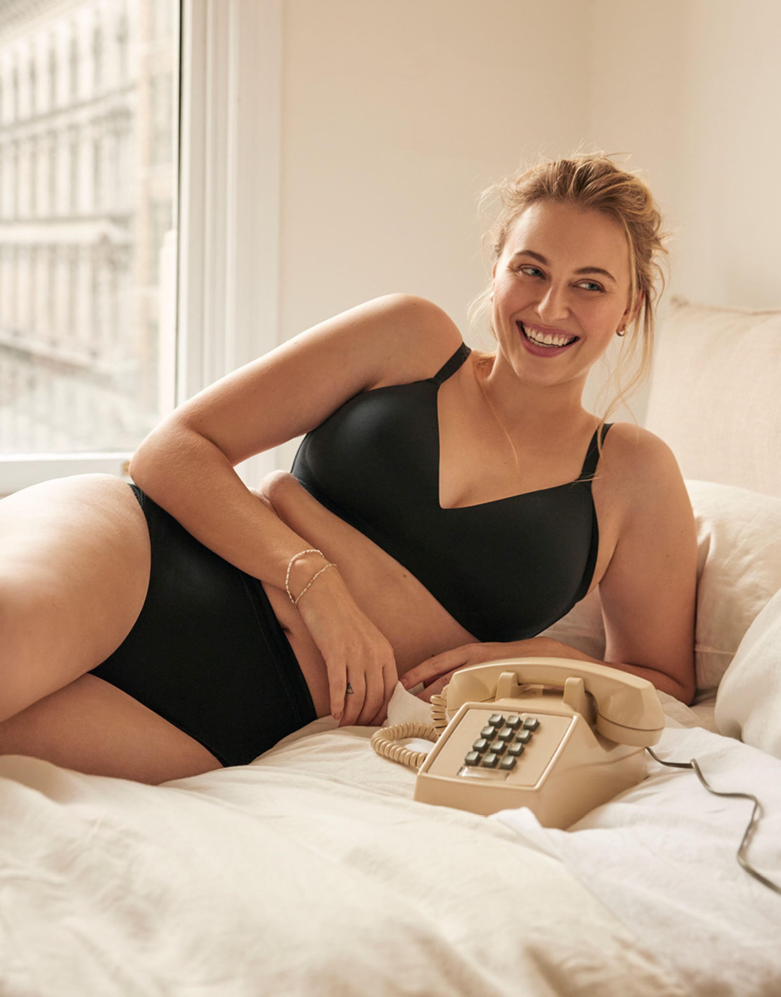 Woman lying on a bed wearing a black WonderBra lingerie set.
