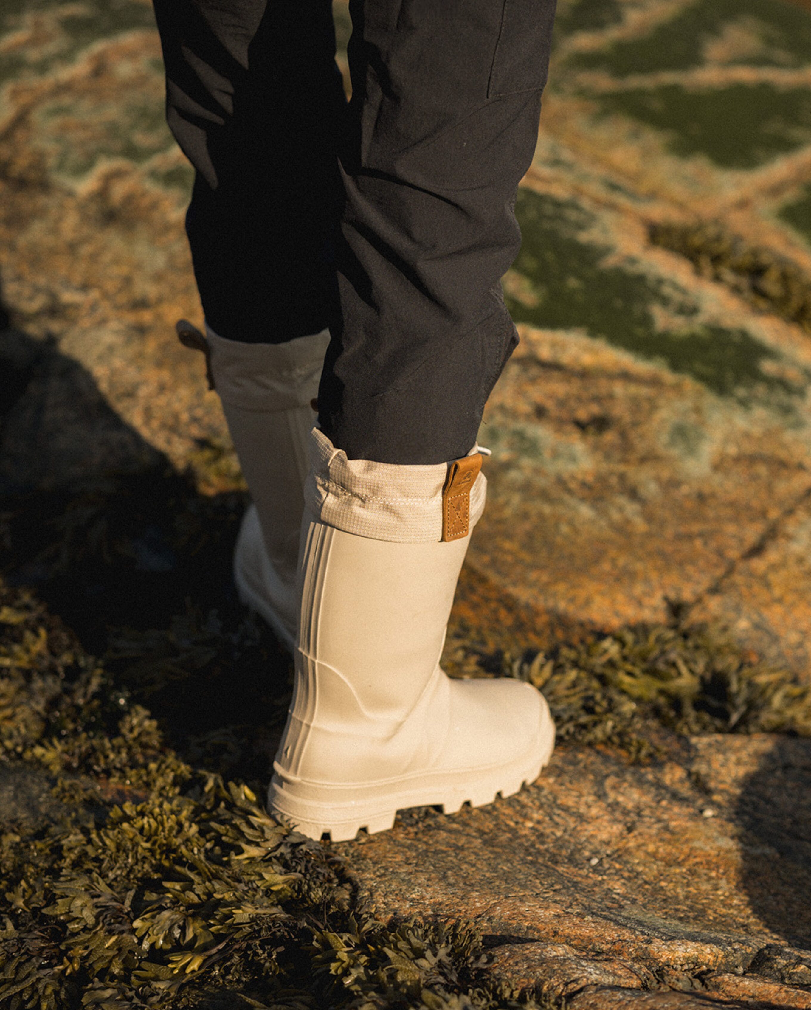 Person wearing beige Tundra boots by Kamik walking on rocks